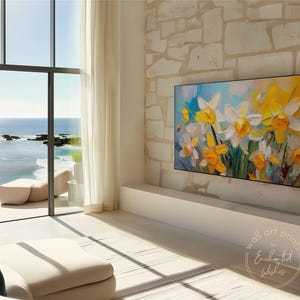 May include: A painting of yellow and white daffodils in a vase, with a blue and white background. The painting is hanging on a wall in a modern living room with a large window overlooking the ocean.