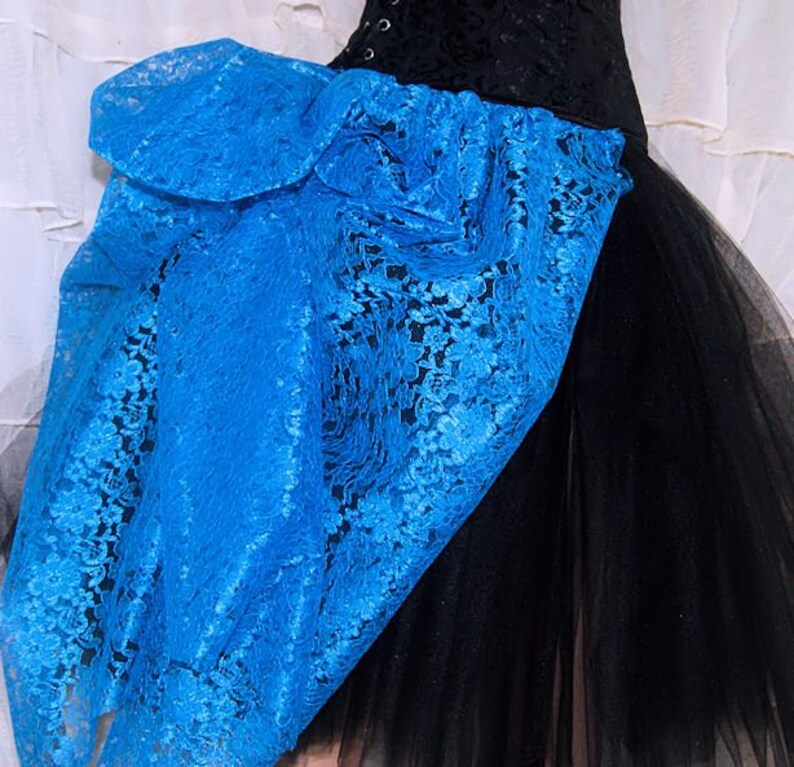 May include: A black tulle skirt with a large blue lace bow on the side. The lace is a delicate floral pattern.