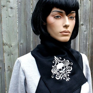 Puede incluir: Un calentador de cuello de vell&oacute;n negro con un dise&ntilde;o de calavera blanca y flores.