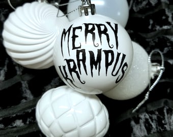 May include: Four white Christmas ornaments, one with the text "Merry Krampus" in black lettering.
