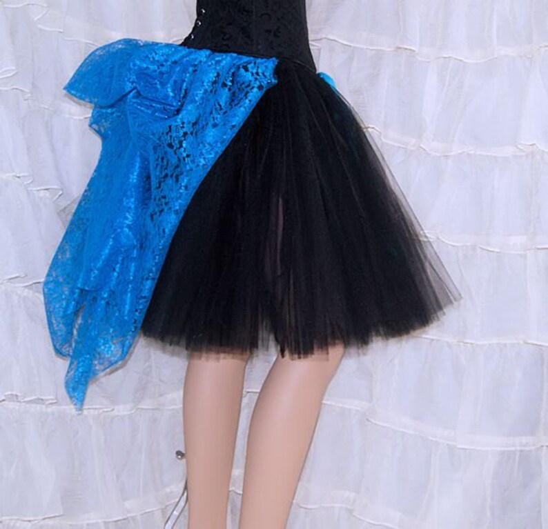 May include: A black tulle skirt with a blue lace overlay. The skirt is short and has a ruffled hem.