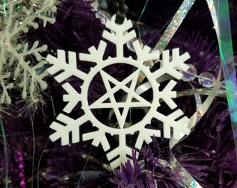 May include: White snowflake ornament with a pentagram in the center, hanging on a purple Christmas tree.