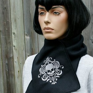 May include: Black fleece neck warmer with a white embroidered skull and floral design.