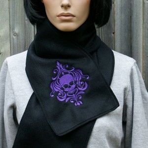 May include: Black fleece scarf with a purple embroidered skull and floral design.