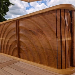 Puede incluir: Un armario de madera con un diseño único y ondulado. El armario está hecho de madera de cerezo y tiene un acabado natural. El armario está cerrado y tiene un diseño decorativo en la parte delantera.