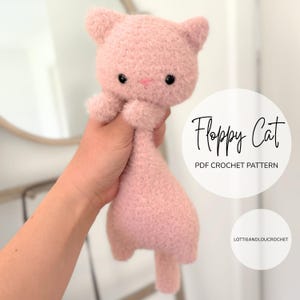 May include: A soft, pink, plush cat toy with black eyes and a pink nose. The cat has a floppy body and small arms and ears. The text "Floppy Cat PDF Crochet Pattern" is in a white circle.