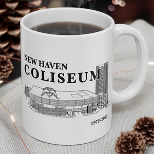 Op de afbeelding: Witte keramische koffiemok met een zwarte omtrek van het New Haven Coliseum en de tekst "NEW HAVEN COLISEUM 1972-2002".