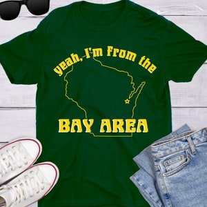 Może przedstawiać: Zielony T-shirt z żółtym obrysem stanu Wisconsin i tekstem "yeah, I'm from the Bay Area".