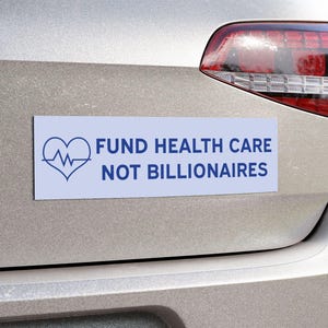 May include: A rectangular white bumper sticker with blue text and a heart-shaped graphic. The text reads "FUND HEALTH CARE NOT BILLIONAIRES". The sticker is affixed to the back of a silver car.