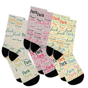 May include: A collection of crew socks with a repeating pattern of the words "Trump" and "fuck" in various colors. The socks have black heels and toes, and the text is in a handwritten style.