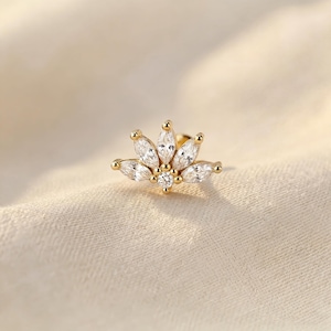 May include: A gold-toned stud earring featuring a fan-shaped arrangement of five marquise-cut clear stones and one small round-cut clear stone at the base. The metal setting is polished gold, creating a delicate and symmetrical floral-inspired design.