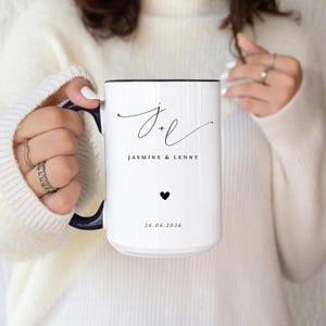 May include: White ceramic mug with a black rim and handle, featuring the initials "J + L" in elegant script, the names "Jasmine & Lenny", a black heart, and the date "26.06.2026".