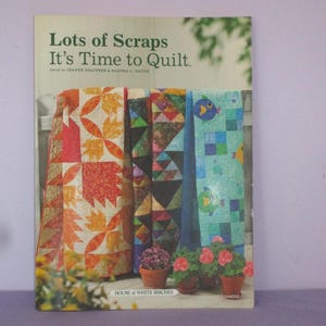 May include: Book cover with the title "Lots of Scraps It's Time to Quilt."  The cover features a colourful patchwork quilt with a variety of patterns and colours. The book is published by House of White Birches.