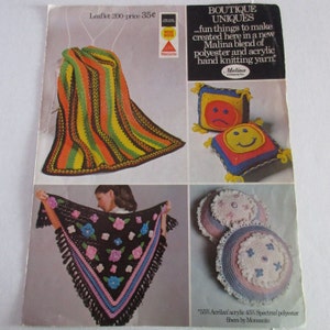 May include: A crochet pattern booklet featuring a striped blanket, a shawl with floral accents, and a set of crocheted pillows with smiley faces. The booklet is titled "Boutique Uniques" and features the text "...fun things to make created here in a new Malina blend of polyester and acrylic hand knitting yarn."