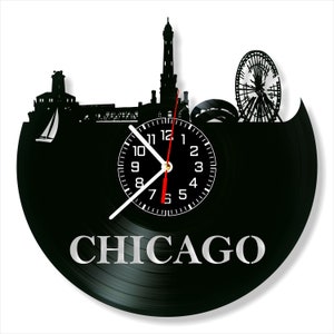 May include: Black vinyl record clock featuring a Chicago skyline silhouette. The clock face has white numerals and hands, with a red second hand. The word "CHICAGO" is displayed in silver letters below the clock face. The clock is a unique decorative item.