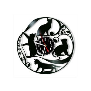 May include: A circular wall clock crafted from a black vinyl record featuring intricate cutouts of four cats in various poses. The center displays a black clock face with white numerals from 1 to 12, white hour and minute hands, and a red second hand.