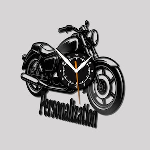 Könnte beinhalten: Schwarze Motorrad-Wanduhr mit rundem Zifferblatt. Die Zeiger sind weiß und orange. Das Wort "Personalisierung" befindet sich unter dem Motorrad. Die Uhr ist auf grauem Hintergrund montiert.