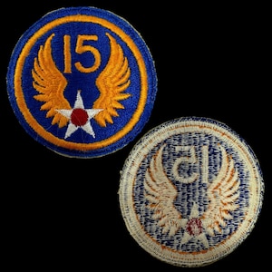 Peut inclure: Deux patchs militaires vintage avec des fonds bleus et des étoiles blanches. Un patch a un cercle jaune avec le numéro "15" et des ailes jaunes. L'autre patch a un cercle jaune avec la lettre "G" et des ailes jaunes.