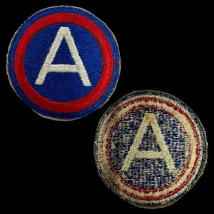 May include: Two vintage military patches with a white "A" in a blue circle with a red outer ring. The patches are made of woven fabric.