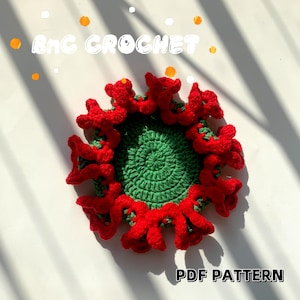 May include: A crochet coaster with a green centre and a red, flower-shaped border. The text "PDF PATTERN" is printed below the coaster.