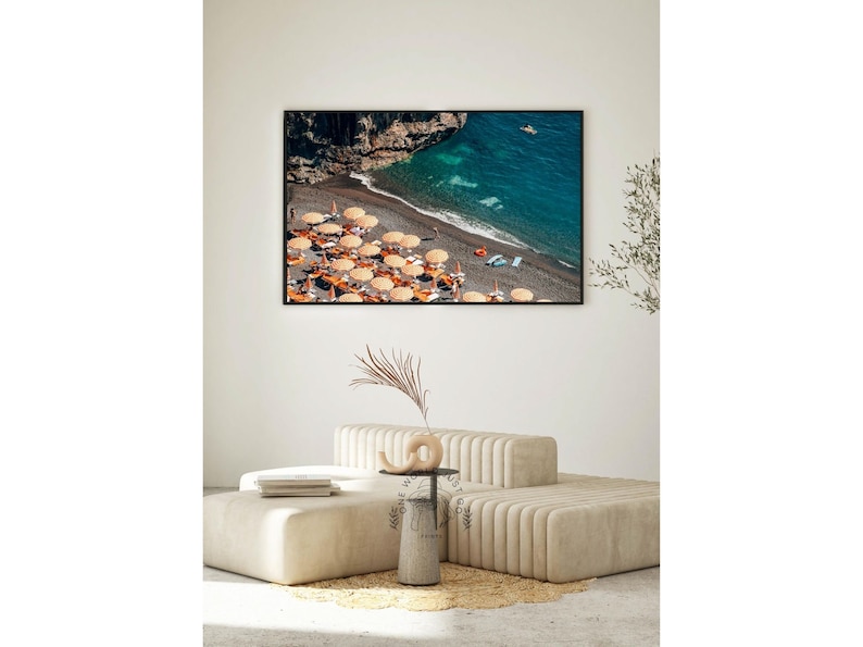 May include: An aerial view of a beach with turquoise water, a rocky cliff, and a line of orange and white beach umbrellas.
