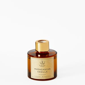 May include: A brown glass bottle with a gold lid and label. The label reads "Sage Botanicals" and "Madagascan Vanilla Luxury Diffuser".