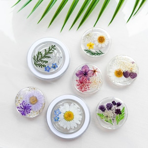 Puede incluir: Seis posavasos redondos de resina transparente con diferentes diseños de flores prensadas. Los posavasos presentan una variedad de flores, incluyendo margaritas, helechos y lavanda.