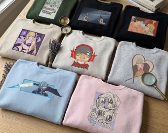 Può includere: Una collezione di otto felpe girocollo in vari colori, tra cui verde oliva, nero, beige, azzurro, grigio e rosa. Ogni felpa presenta una stampa grafica unica, che spazia da personaggi in stile anime a disegni astratti.