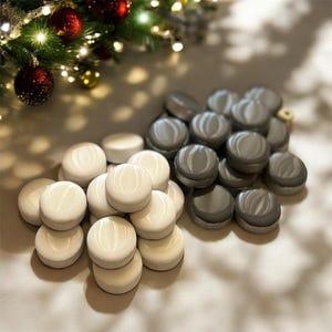 Può includere: Primo piano di due pile di piastrelle rotonde, decorative e in ceramica. Una pila è bianca e l'altra è grigia. Le piastrelle hanno una finitura liscia e lucida.