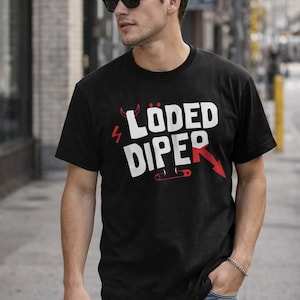 May include: Black crew neck t-shirt with the words "LÖDED DIPER" in white, with red accents including a lightning bolt, devil horns, and an arrow. The shirt is worn by a person wearing sunglasses.