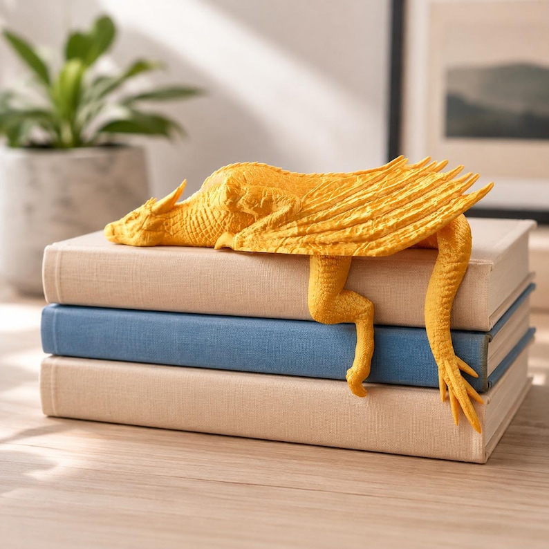 May include: A bright yellow dragon figurine with textured scales and wings resting on top of a stack of three hardcover books. The dragon is positioned horizontally, with its legs and tail draped over the edge of the top book.