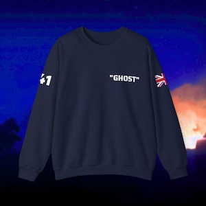 Puede incluir: Una sudadera azul marino con texto blanco que dice "GHOST" en la parte delantera. La manga izquierda tiene un "41" blanco y la manga derecha tiene una pequeña bandera del Reino Unido.