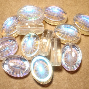 May include: A collection of clear, iridescent oval and rectangular beads. The beads have a faceted design that catches the light, creating a rainbow effect. These beads are suitable for jewelry making and crafts.
