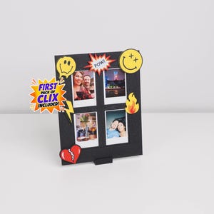 May include: A black square photo frame featuring four rectangular slots for pictures. The frame is decorated with colorful pop-art style icons including smiley faces, a flame, a broken heart, and a starburst with the text FIRST PACK OF CLIX INCLUDED!
