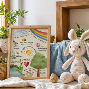 May include: A watercolor print with a light blue background and a rainbow at the top. The print features a tree with a sun and the words "My light warms the world". The print also includes text with positive affirmations, such as "I let worries float away" and "I am transforming beautifully".
