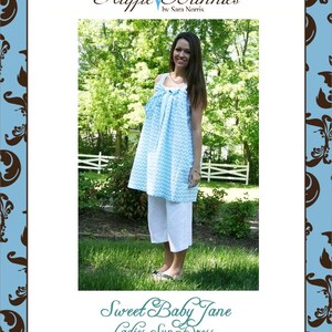 Op de afbeelding: Een blauwe en witte chevron-zonnejurk met een geplooide halslijn en een witte strik. De jurk wordt getoond op een model in een grassige buitenomgeving. De tekst "Sweet Baby Jane Ladies Sun Dress Size 2-14" is onder de afbeelding gedrukt.