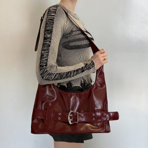 Cartera de hombro de piel color burdeos y rojo cereza con detalle de hebilla