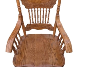 May include: A medium-brown wooden armchair featuring a high backrest with intricate carved floral and scroll patterns. The chair includes a contoured seat, curved armrests, and a series of vertical spindles connecting the seat to the backrest.