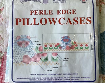 May include: A Jack Dempsey Needle Art package for Perle Edge Pillowcases, pattern #263 Tulip Teddy. The white packaging features red text, a graphic of a teddy bear in a hat, and a row of tulips. It includes one pair of standard size pillowcases.