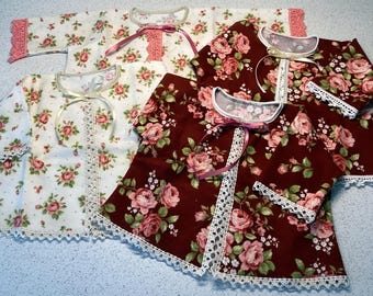 May include: Three short-sleeved jackets featuring floral patterns in shades of pink, green, and white. Two jackets have a dark maroon background, while one has a white background. Each jacket includes a lace trim, a round neckline, and a ribbon tie.