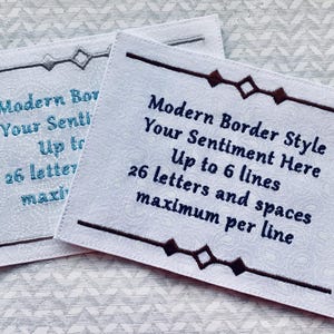 May include: Two white fabric tags with decorative borders and text. The text reads "Modern Border Style, Your Sentiment Here, Up to 6 lines, 26 letters and spaces maximum per line."