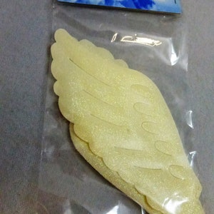 May include: Two white glitter angel wings in a clear plastic bag. The bag has a blue and white label that says "Darice Angels".