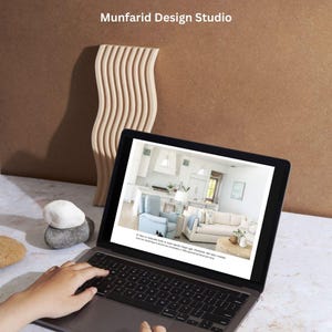 Op de afbeelding: Een laptop met een wit toetsenbord en een zwart touchpad. De laptop is open en toont een website met een afbeelding van een woonkamerinterieur. De tekst op de website luidt: "Een mix van natuurlijke vormen en een rustige, handgekozen kleurenpalet bieden een onderscheidende sfeer met subtiele warmte. Een gastvrije sfeer wordt gecre&euml;erd door een mix van texturen en patronen. Details zijn belangrijk en zorgen voor een samenhangende look."