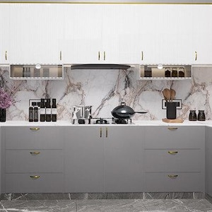 May include: A modern kitchen with grey cabinets and white upper cabinets. The kitchen features a marble backsplash, a stainless steel hob, and a black frying pan.