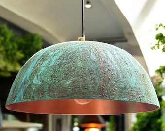 May include: A copper and green dome-shaped pendant light fixture with a textured finish. The light is hanging from a black cord and has a warm white light bulb inside.