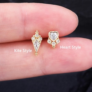 May include: Two gold-colored earrings, one kite-shaped and one heart-shaped, each adorned with clear, sparkling gemstones. The kite-shaped earring has a central diamond-shaped stone. The text "Kite Style" and "Heart Style" are visible.