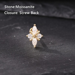 May include: A gold-colored stud earring with a floral design. The earring features a central marquise-cut moissanite stone, surrounded by four smaller round stones. The text on the image reads "Stone: Moissanite" and "Closure: Screw Back".