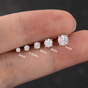 Può includere: Una collezione di sei orecchini a lobo rotondi e trasparenti in zirconia cubica di varie dimensioni, da 2 mm a 5 mm. Gli orecchini sono incastonati in un metallo color argento.