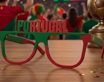 May include: Novelty glasses featuring the word PORTUGAL in red and green block letters across the top frame. The frames are colored in a red and green pattern, with a small gold emblem on the temple arm, designed for sports fan spirit.