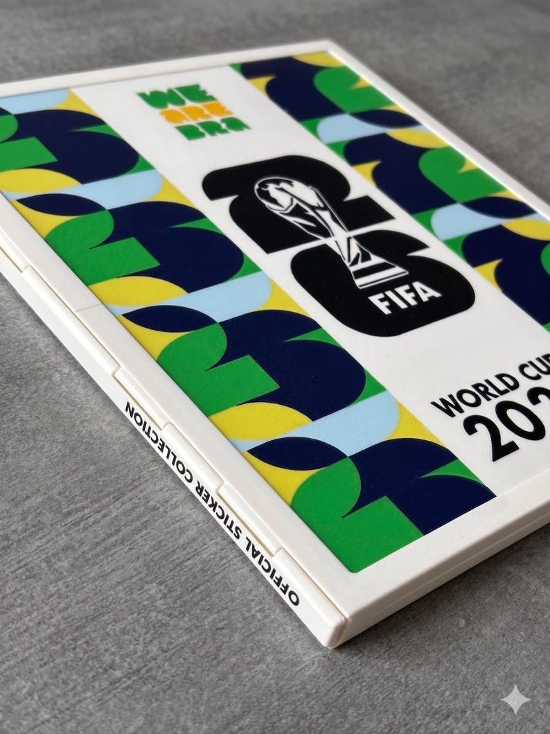 May include: A white rectangular FIFA World Cup 2022 official sticker collection album. The cover features a geometric pattern in green, yellow, blue, and light blue, with the FIFA World Cup trophy icon and the text WE ARE BRA and 2022.